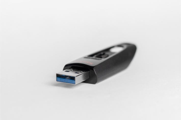 USB-флешка, лежащая на столе: напоминание о том, чтобы не использовать неизвестное съемное хранилище файлов для предотвращения атак вирусов-вымогателей